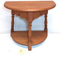 Front angle view of the vintage wooden half-circle side table showing turned legs and lower shelf.
