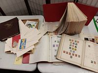 Overview of brown hardcover album, wooden tray of envelopes and red binder on table