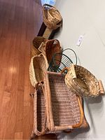 Various woven baskets including three-tier wicker basket stand, round basket with wooden handles, and green wire basket.