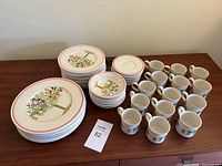 Full dishware set with plates and mugs arranged on wooden table.