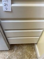 Closed white kitchen drawers where utensils are stored.