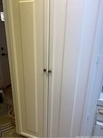 Closed view of the white cabinet containing the items.