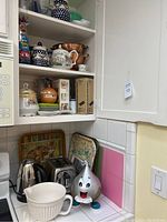 Wide shot of cabinet and countertop showing multiple kitchen items including ceramic containers and decorative tins