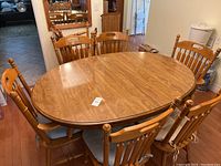 Full view of oval dining table set with chairs and mirror in background