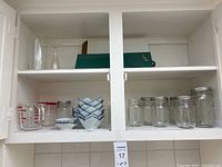 Upper cabinet with glass jars, measuring cups, and blue accent bowls