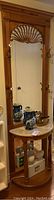 Full view of wooden hall tree with carvings and mirror, marble top table at base with decorative items on top