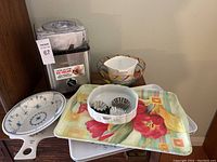 Overview of Cuisinart ice cream maker, trays, glass and ceramic bowls, tart pans on a table.