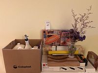 Photo of miscellaneous kitchen and decorative items on shelf, including ceramic containers, oil dispenser, wooden trays, boxed items, and dried flower vase.