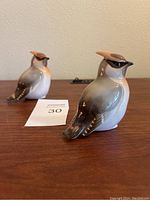 Front angle view of two Lomonosov porcelain jay bird figurines on a wooden surface with auction lot number card.