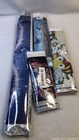 Four rolled and wrapped diamond painting kits showing various designs including floral and bees.