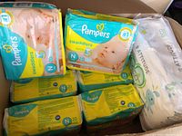 Photo showing eight packs of Pampers Swaddlers Newborn diapers and one pack of Attitude Eco baby diapers in a box.
