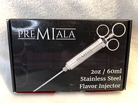 Box front showing Premiala brand, model 20oz/60ml stainless steel flavor injector