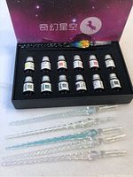 Boxed set containing 12 ink bottles and 5 glass pens with textured handles inside a starry-themed box.
