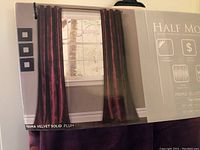 Photo of the packaged Prima Velvet curtains showing two panels hanging on a rod in plum purple color.