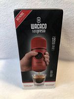 Front of box showing Wacaco Nanopresso portable espresso device in red, dispensing espresso into glass, with 18 bar pressure and 260 PSI stated.