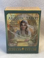 Front of the sealed Akashic Tarot box showing title, authors, and cover artwork of a woman holding a scroll.