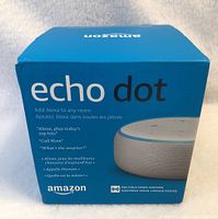 Front view of the sealed Amazon Echo Dot box showing branding, product image and feature highlights.