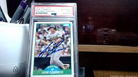 Front side of the Jose Canseco signed card showing the player batting and signature in blue ink, encapsulated and certified by PSA.