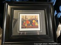 The full black framed print with visible glass and black matting showing a colorful nature scene.