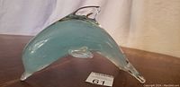 Side view of blue dolphin Murano glass figurine showing smooth translucent blue glass and clear fin and tail highlights.