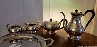 Full set arranged on table showing five pieces: coffee pot, teapot, sugar bowl, creamer and tray