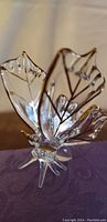 Side angle of crystal butterfly showing clear glass with gold detailing on wings and legs.