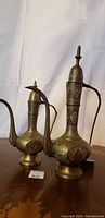 Two antique Persian bronze ewers side by side showing shape and size contrast