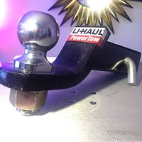 Close-up angled view of U-Haul 2-inch ball hitch and slider showing the PowerTow label and polished metal ball.
