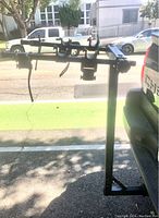 Side view of the black Hollywood Racks hitch-mount bike rack attached to vehicle, showing padded hooks for holding bikes.