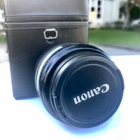 Canon 50mm Compact-Macro EF lens with black Canon lens cap and black carrying case visible in background.