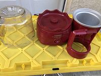 All parts of the ice cream maker assembled together: main red motor unit, clear lid, silver mixing bowl with red handle, and mixing paddle.