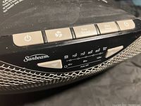 Close-up of heater control panel showing power, fan, Eco Smart, Max Heat buttons, temperature settings from 70°F to 85°F and timer up to 12 hours.