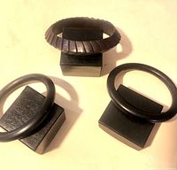 Photo of three wooden bracelets displayed on black stands, showing the overall shape and design of the items.