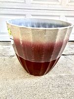 Front view of large outdoor planter pot showing ribbed reddish lower half and beige upper half with gray interior.