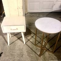 Overview of the white nightstand and round table placed on concrete floor.