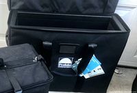 View of the open ProFoto Transit light case showing black padded interior and top-loading lid, with tags attached.