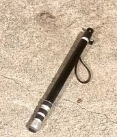 Photo of pro camera monopod lying on concrete surface, showing overall structure and wrist strap.