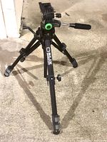 Front angle view showing tripod fully set up with legs adjusted and pan handle visible