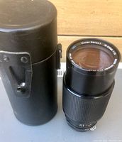 Vivitar Series 1 70-210mm zoom camera lens shown standing next to its black cylindrical carrying case.