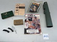 Wide view showing all lot items including manuals, monocular, cutters, first aid dressing, cleaning kit, and micrometer box.