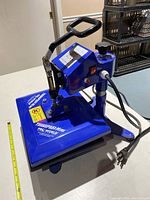 Blue tabletop Pro World TransPro Mini heat press at slight angle showing platen, base, lever handle, power cord.