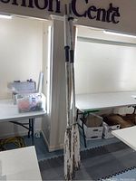 Two wooden oars leaning against a pillar, showing their full length and distressed white paint.