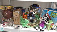 Shelf display of all items, clear view of football, mugs, plates, plush, and boxed Snoopy machine