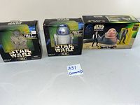 Front view of Yoda, R2-D2, and Han Solo with Jabba the Hutt boxed figures arranged on a plain gray surface with a lot number card in the middle.
