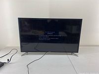 Front view of the 32 inch Samsung TV powered on in no cable mode showing 'No Cable Connected' message on screen, set on table with power cord connected.