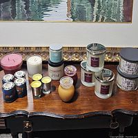 Full view of assorted candles displayed on a wooden surface showing a variety of sizes, colors, and brands.
