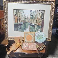 Photo showing six decorative pieces including the large framed Venice canal print, two wooden pieces, a square ceramic tile, round floral plate, and marble tray.