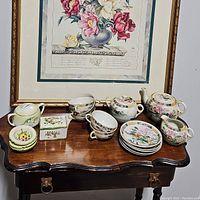 Wide view of table with all decorative pieces including the teaset, trinket box, other small plates, and lidded container.