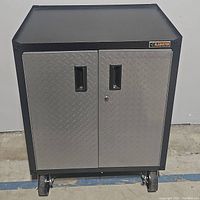 Front view of Gladiator metal storage cabinet with two diamond plate silver doors and caster wheels.