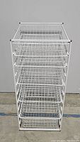 Front view of white wire basket storage unit showing the full height and six wire baskets.